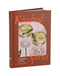 Kindred Spirits from Chronicle Books is a drinks book for couples, featuring date night cocktails on the cover with two glasses garnished with lime and mint against a pink background.