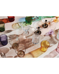 The Kindred Spirits glassware collection from Chronicle Books fills a sunlit surface with colorful cups, bowls, and candleholders—casting vibrant shadows and inspiring creative date night cocktails for couples.
