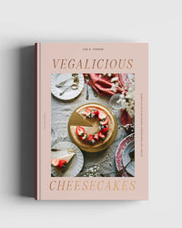 Vegalicious Cheesecakes – Bakery-Style & Plant-Based by Cozy Publishing showcases a sliced vegan cheesecake topped with strawberries—ideal inspiration for egg- and dairy-free, plant-based baking and desserts.