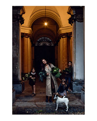 A woman with leafy greens stands under an arched doorway with three children and a white dog. The scene, glowing warmly, evokes happy family moments and the timeless charm of Old World Italian by Random House.