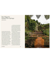 At Hot Springs by Random House, guests relax in mineral-rich, orange-hued pools nestled in a lush tropical setting, surrounded by greenery and palm trees, enjoying the tranquil natural environment.