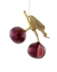 The Cody Foster Cultivated Fig - Gold Leaf is a hand-crafted decoration featuring two purple figs with gold stems and a gold leaf, one sliced open to show its red interior, hanging on a thin gold string.