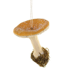 The Cody Foster Yellow Cap Mushroom is a hand-crafted hanging ornament featuring a yellow glass mushroom cap with white spots, a beige stem, moss at the base, and is suspended by a string.
