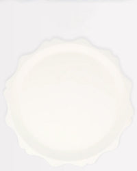 The Meri Meri Cream Decorative Edge Compostable Dinner Plate features a wavy scalloped edge and an elegant design, making it a stylish disposable choice for gatherings.
