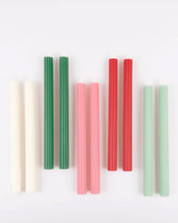 The Meri Meri x Liberty Sweet Meadow Candle Gift Box features six pairs of ridged table candles in white, green, pink, red, and light blue neatly arranged on a plain white background.