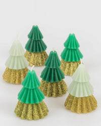 Seven Meri Meri Green Mini Tree Candles in assorted green shades with gold glitter bases are displayed on a white background.