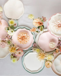 Meri Meri Cream Decorative Edge Compostable Side Plates, arranged on a light tablecloth with blush and cream flowers, create an elegant and delicate flat lay display.
