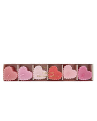 A box of six Meri Meri X Liberty Scalloped Heart Candles in pink and red, each with scalloped edges, comes arranged in clear packaging—an ideal Valentine’s gift from Meri Meri.