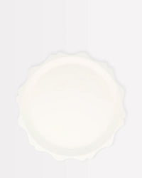 The Meri Meri Cream Decorative Edge Compostable Side Plate is round and white with gently wavy, scalloped edges, shown from above against a plain, light background.