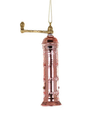 The Cody Foster Copper Pepper Mill Ornament is a shiny, metallic decoration shaped like a classic pepper mill, featuring copper and brass tones, and hangs from a gold string.