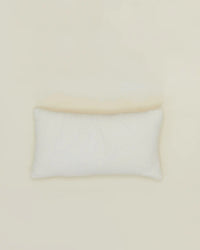The Hawkins New York Simple Linen Pillow (22 x 12 inches, Ivory) with a plush down insert rests on a light beige surface, shot from above with minimal shadows. The machine-washable cover allows for easy care.