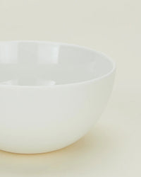 A portion of a Simple Porcelain Large Bowl from Hawkins New York’s set of 4 is shown on a light, neutral background, highlighting its smooth, glossy finish and minimalist style.