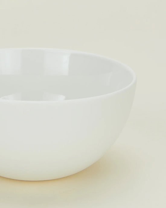 A portion of a Simple Porcelain Large Bowl from Hawkins New York’s set of 4 is shown on a light, neutral background, highlighting its smooth, glossy finish and minimalist style.