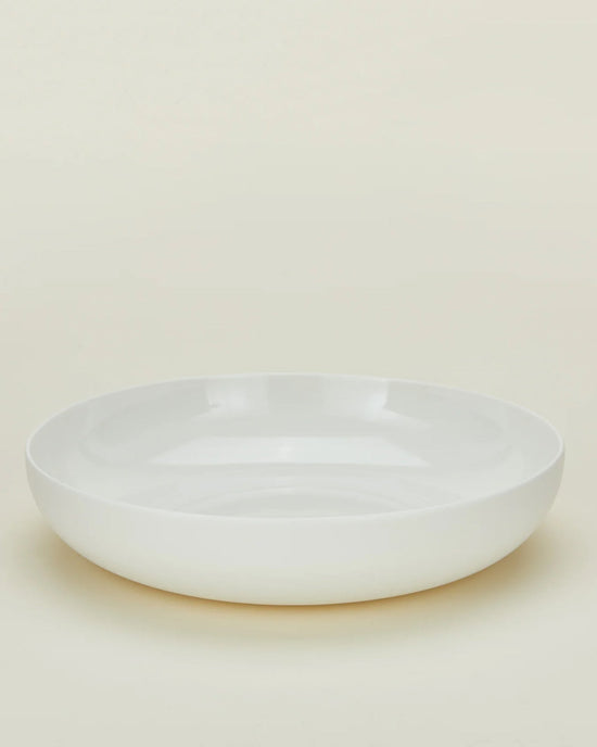A set of 4 Simple Porcelain Low Bowls by Hawkins New York, featuring a plain, round white design with a subtly raised edge, displayed on a light cream background.