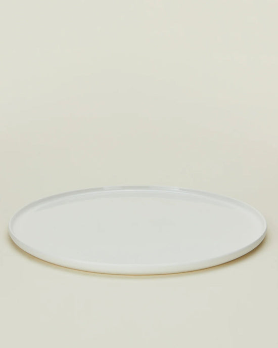 A set of four Simple Porcelain Dinner Plates by Hawkins New York is shown on a light beige background, each plate round, plain, white, and photographed from a slightly elevated angle.