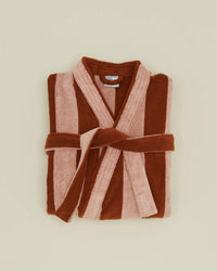 The Hawkins New York Simple Striped Terry Bathrobe in Blush/Terracotta, made of 100% cotton, features wide vertical stripes and a matching waist belt. Displayed folded on a beige background, it combines comfort with stylish design.