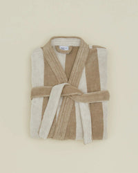 The Hawkins New York Simple Striped Terry Bathrobe in Ivory/Flax, featuring wide beige and cream stripes and a matching waist tie, is shown folded on a light beige background.