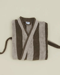 A folded Hawkins New York Simple Striped Terry Bathrobe in light grey and dark grey stripes is displayed against a plain, light background.