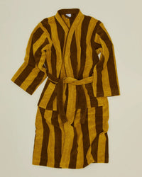 The Simple Striped Terry Bathrobe in Mustard/Bronze by Hawkins New York features long sleeves, a belt, and wide vertical stripes in mustard yellow and brown, shown laid flat on a cream background.