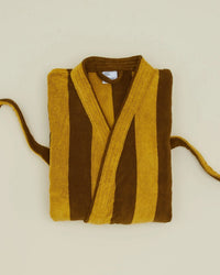 The Hawkins New York Simple Striped Terry Bathrobe in Mustard/Bronze, made of 100% cotton, is folded on a light beige surface with its sleeves and belt visible.