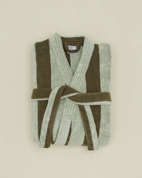 The Simple Striped Terry Bathrobe in Olive/Sage by Hawkins New York, made from 100% cotton for exceptional softness, features light and dark green stripes with a matching front-tied belt and is displayed folded on a light beige background.