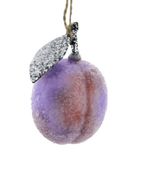 The Cody Foster "Sugared Plum" ornament, a frosted purple and pink glass peach with a glittery silver leaf, hangs by a brown string against a white background.