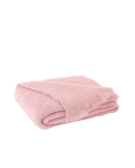 The Brushed Mohair Throw in Lotus by Lands Downunder, woven in New Zealand, features a soft, fluffy texture and is shown neatly folded in light pink against a white background.