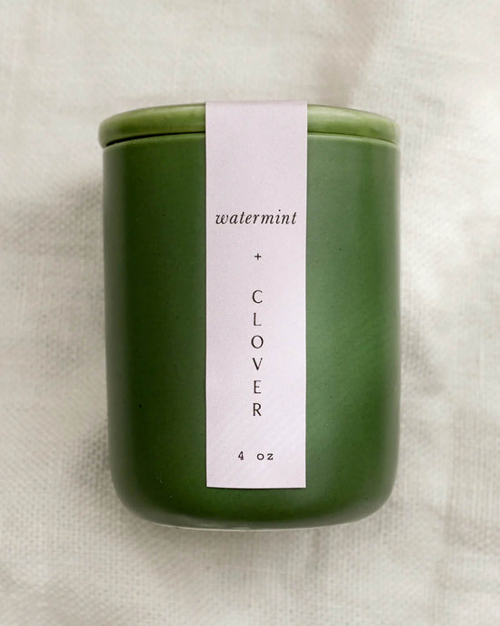 The LEIF Watermint & Clover Candle is a green 4 oz reusable ceramic jar with a white label, made from a soy wax blend, and displayed on a lightly textured surface.